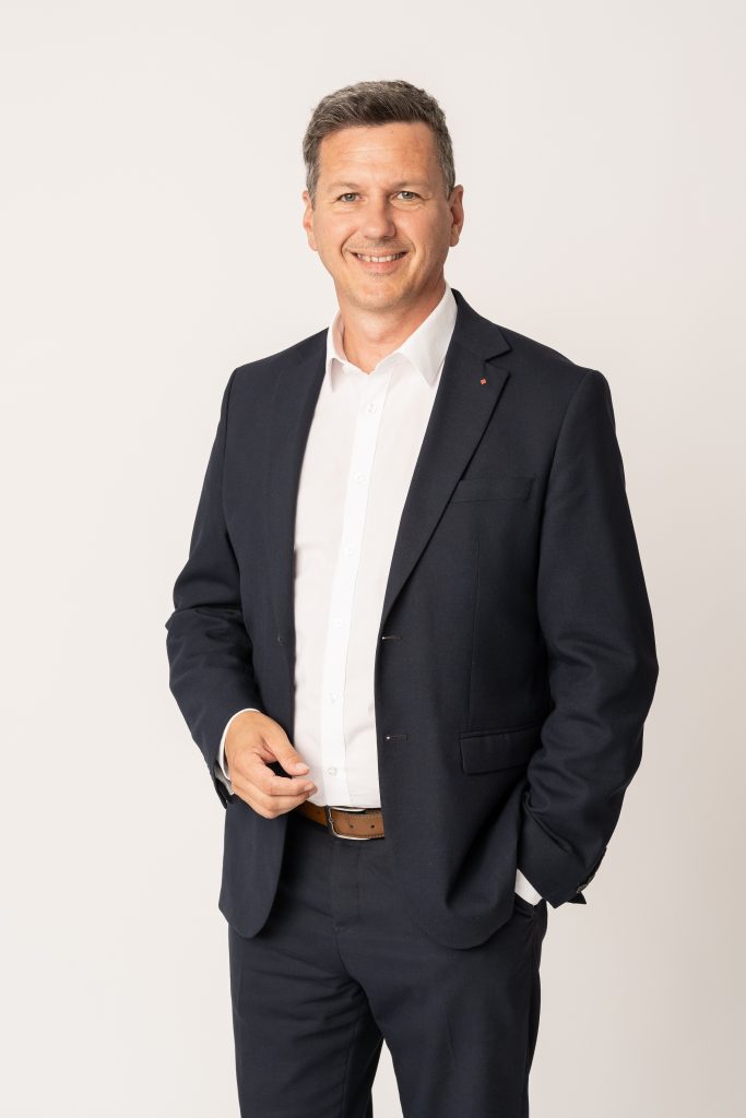 Landesrat Daniel Fellner im dunkelblauen Anzug, lächelnd im Halbportrait,